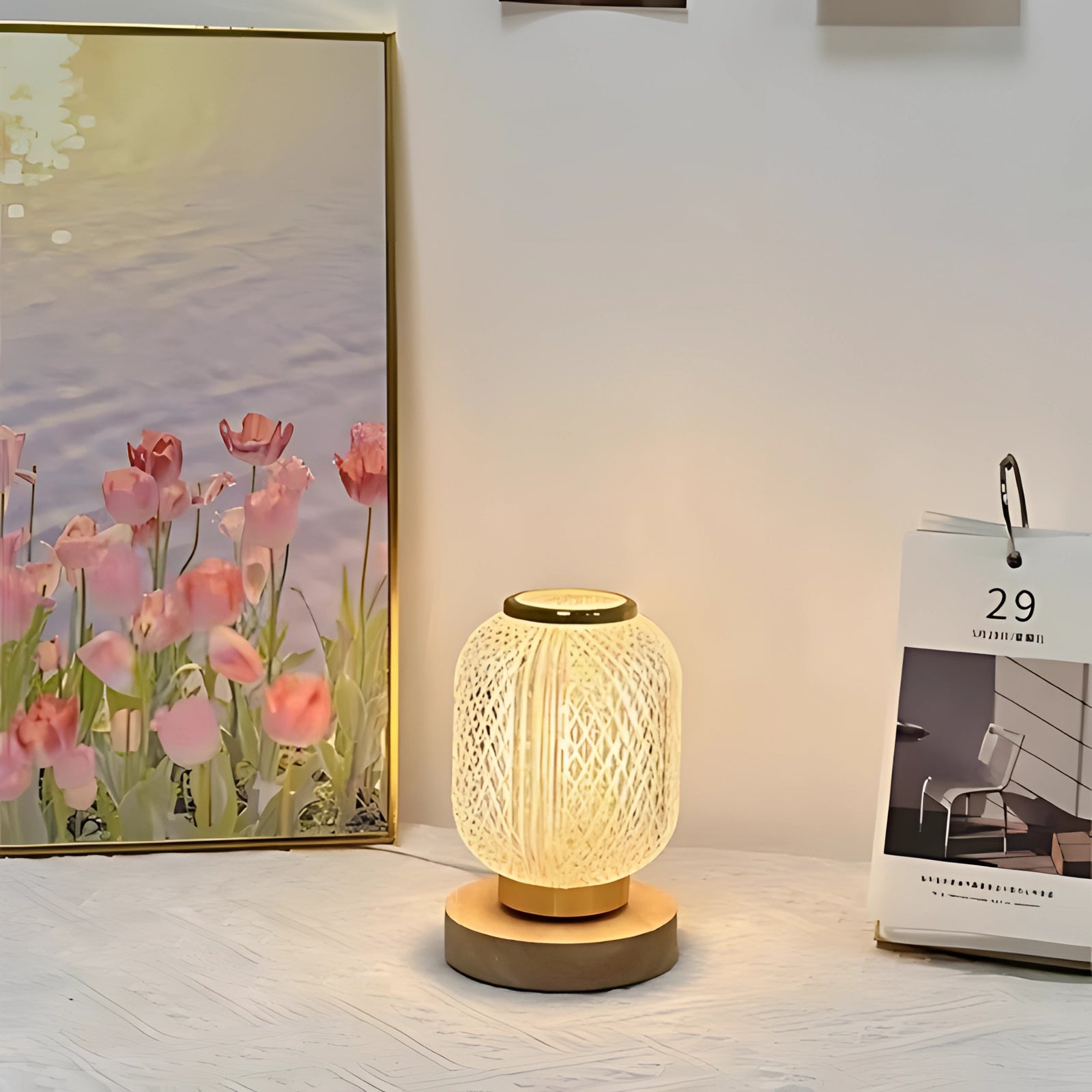 Modern woven bedside lamp with an elegant design, placed on a wooden nightstand beside a decorative flowerpot and framed artwork, enhancing the interior design of a bedroom.