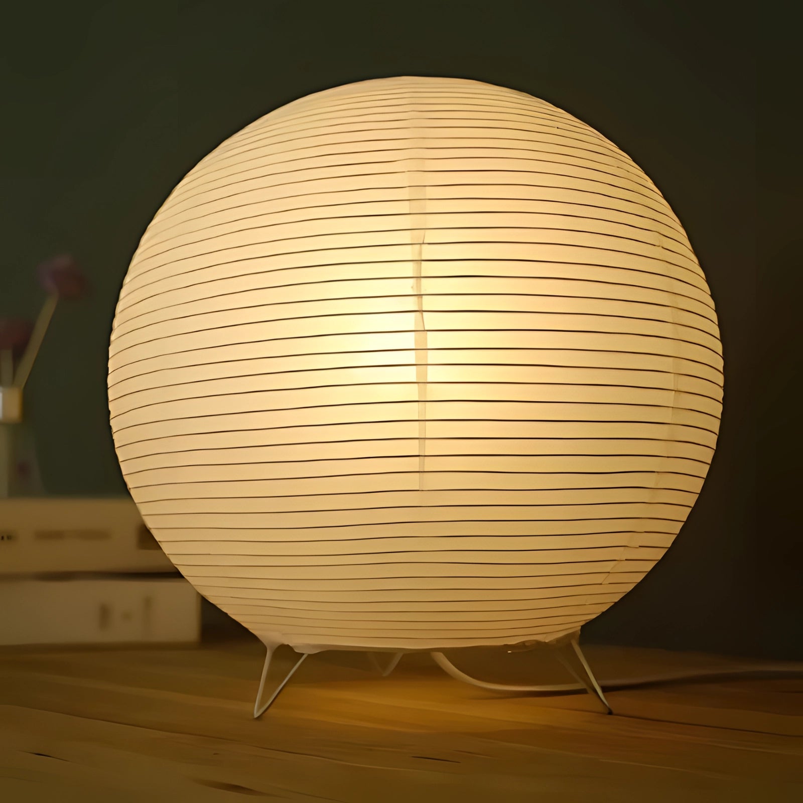 Modern Zen oval paper lamp with a wooden base, featuring a soft lampshade that emits ambient lighting, suitable for contemporary decor settings, with a nearby plant enhancing the aesthetic.