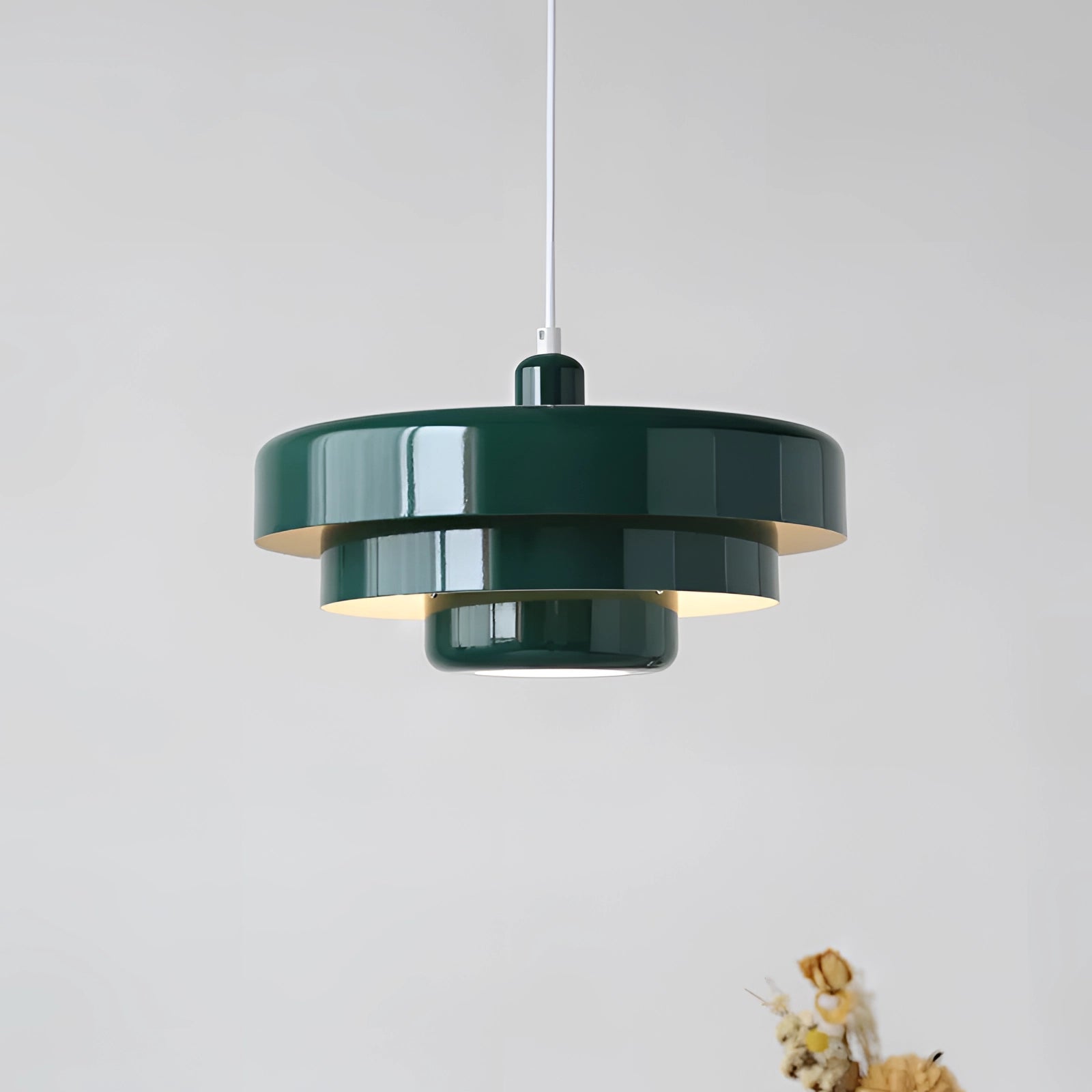 A green mid-century modern Scandinavian pendant light with a sleek, cylindrical design, suspended from the ceiling.