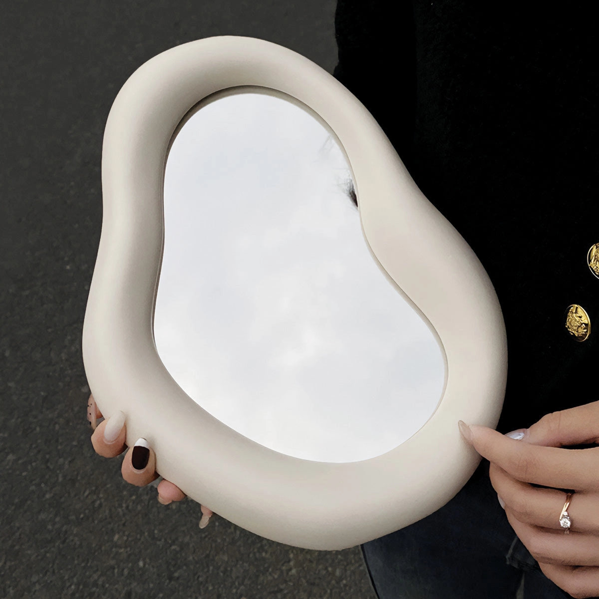 Organic asymmetrical mirror with a modern minimalist design, featured as a stylish vanity decor piece. The mirror has a unique shape with sleek metal edges, complementing contemporary interior design aesthetics. The reflective surface is unobstructed, capturing a clear and accurate reflection.