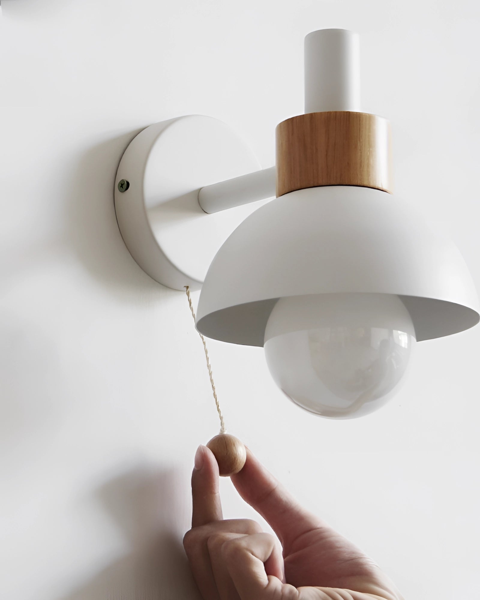 Pastel Scandinavian adjustable wall lamp with minimalist color block design mounted on a wooden wall plate near a potted plant.
