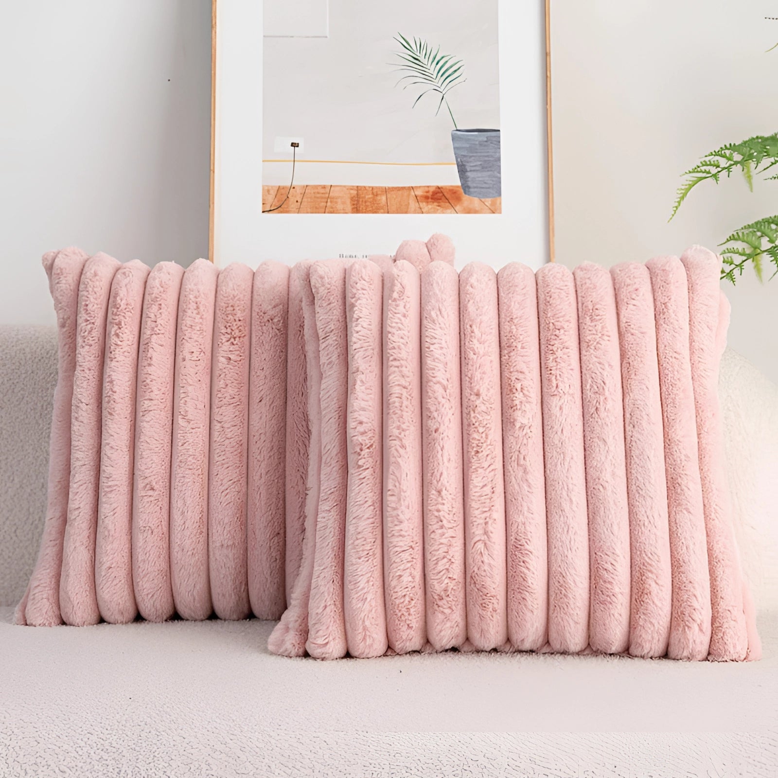 Pink corduroy pillow with soft ribbed texture placed on a studio couch, surrounded by a plant and wooden table, creating a cozy and decorative setting.