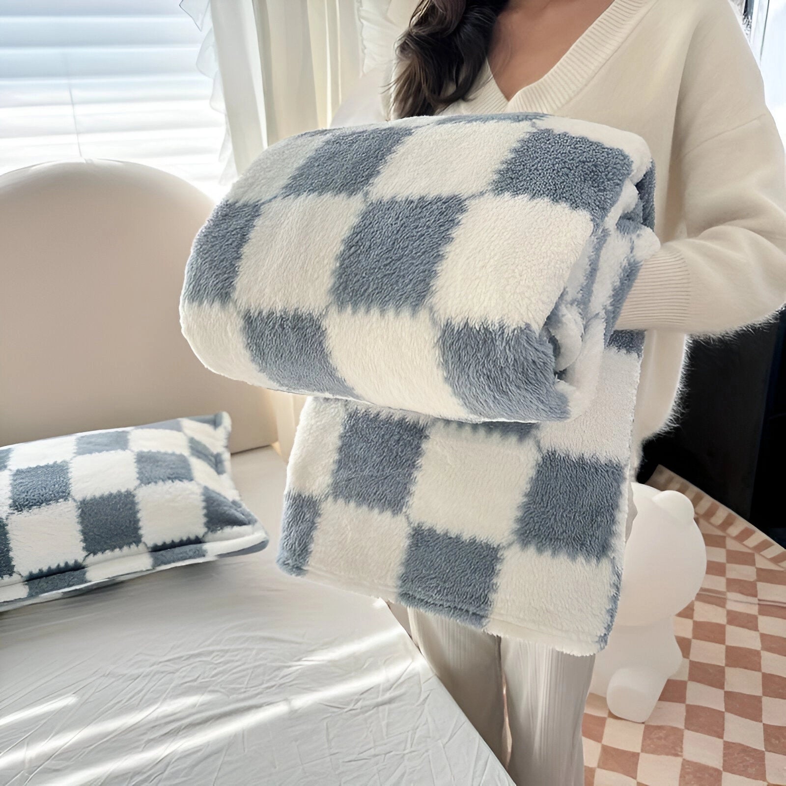 A blue fleece blanket with a checkered pattern, measuring 200 x 230 cm, displayed draped over furniture in a cozy setting. The blanket appears soft and plush, providing a comfortable and decorative touch to the room.