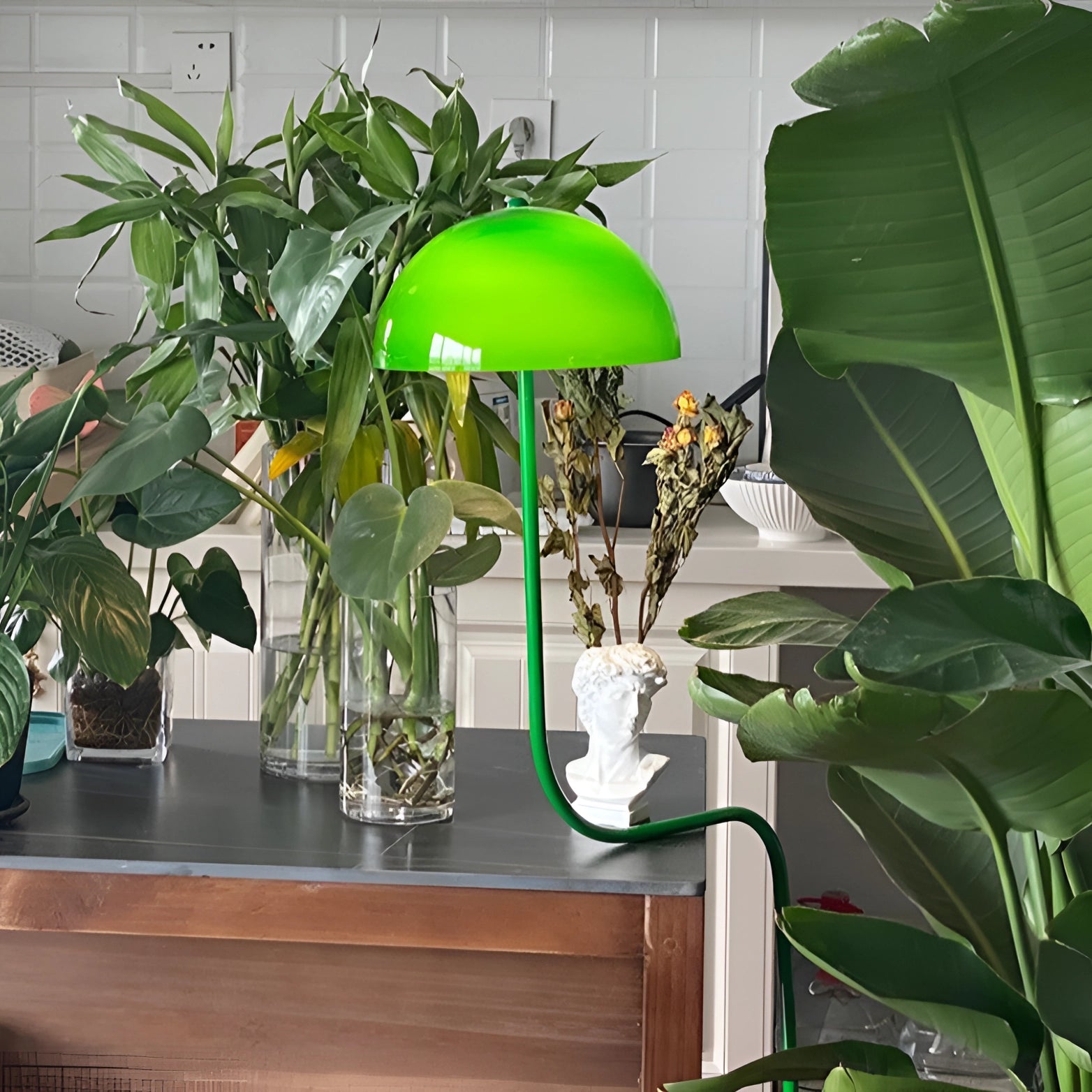 A Retro Art Deco green brass floor lamp placed next to a lush green houseplant in a stylish room setting, highlighting the elegant home decor.
