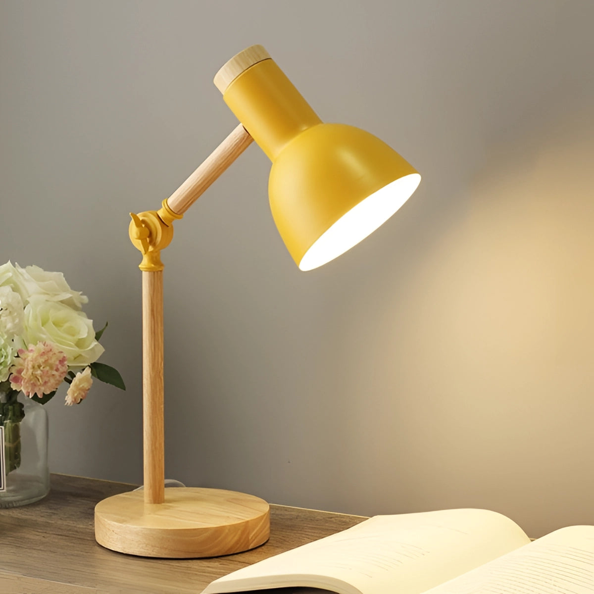 Scandinavian wooden adjustable LED desk lamp in retro style with a yellow finish, featuring a three-color switch, elegantly positioned on a tabletop. The lamp's wooden structure and sophisticated design provide both comfort and balance, blending well with surrounding flowers and plants, enhancing the artistic ambiance of the space.