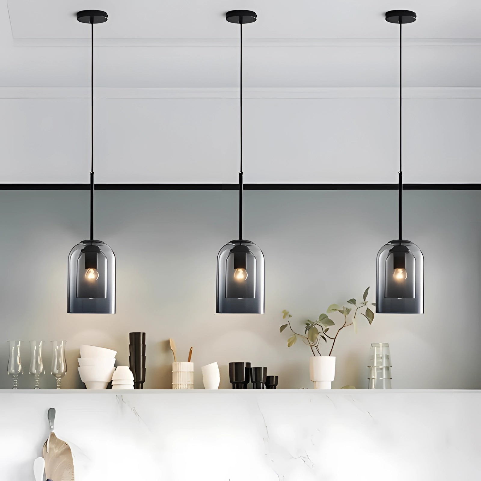 Modern smoke glass pendant light hanging in a room, featuring a transparent Edison bulb. The light is surrounded by houseplants and decorative elements like a shelf, picture frames, and a window, creating a stylish and contemporary ambiance.