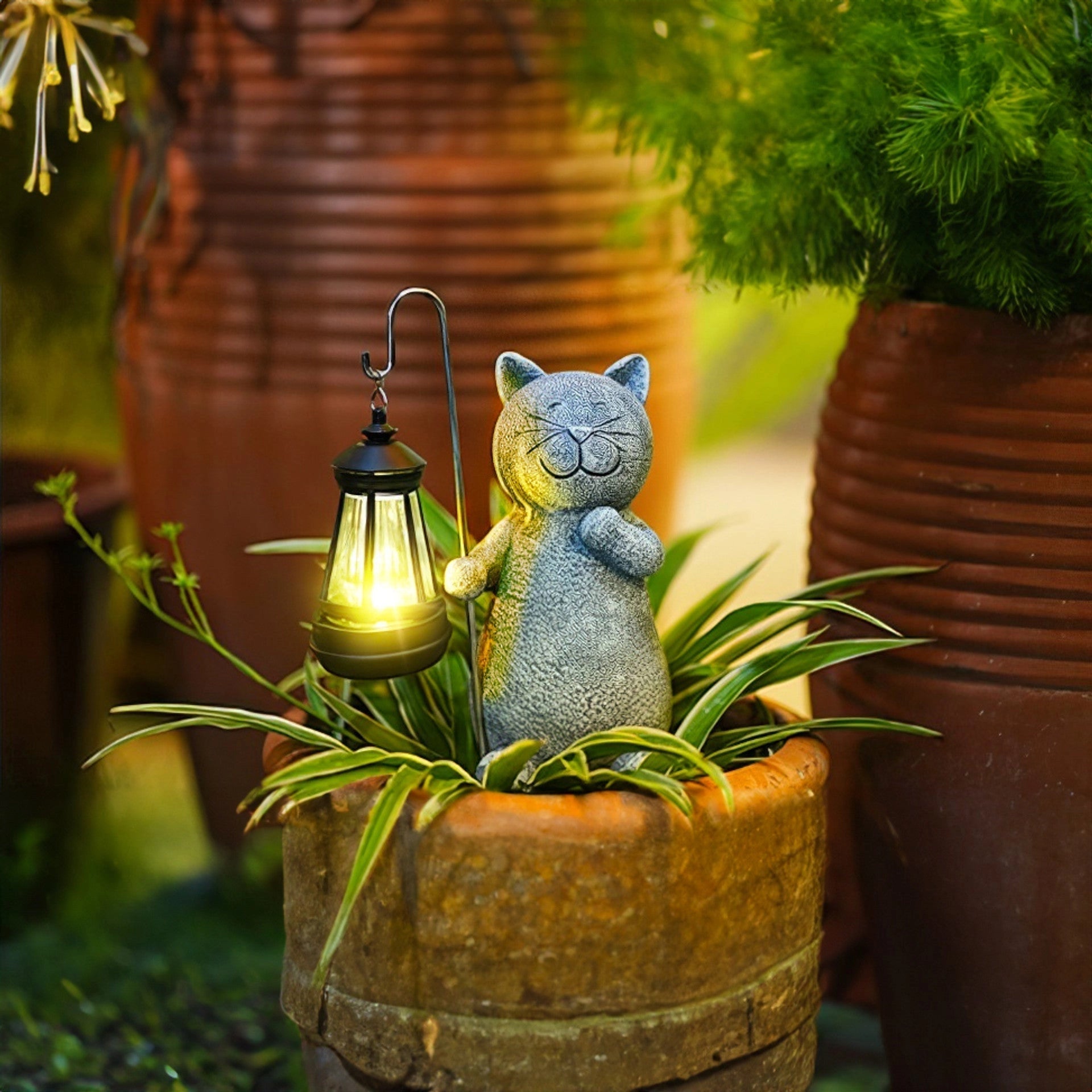A whimsical solar-powered cat lantern placed outdoors in a garden setting, surrounded by plants and grass, providing eco-friendly lighting at night.