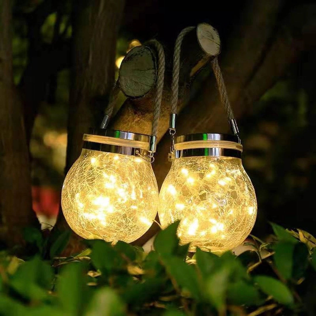Solar Mason Jar Lights illuminating a garden setting with a soft glow, surrounded by twigs, grass, and terrestrial plants, creating a magical outdoor ambiance.