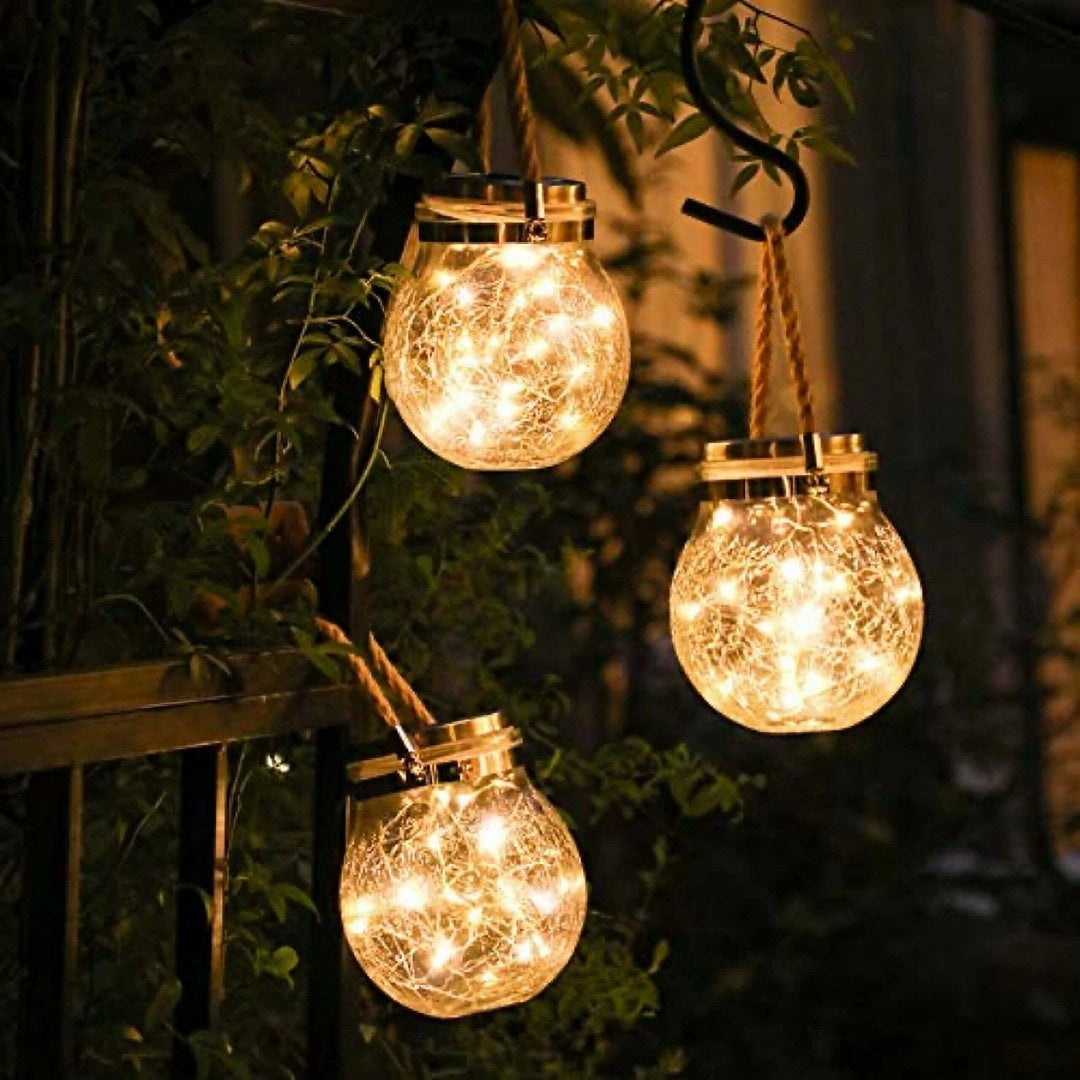 Solar mason jar lights featuring warm amber LED fairy lights, nestled within the jar to create a charming lantern effect, suitable for outdoor use, waterproof design, surrounded by twigs and branches for an enchanting rustic look.