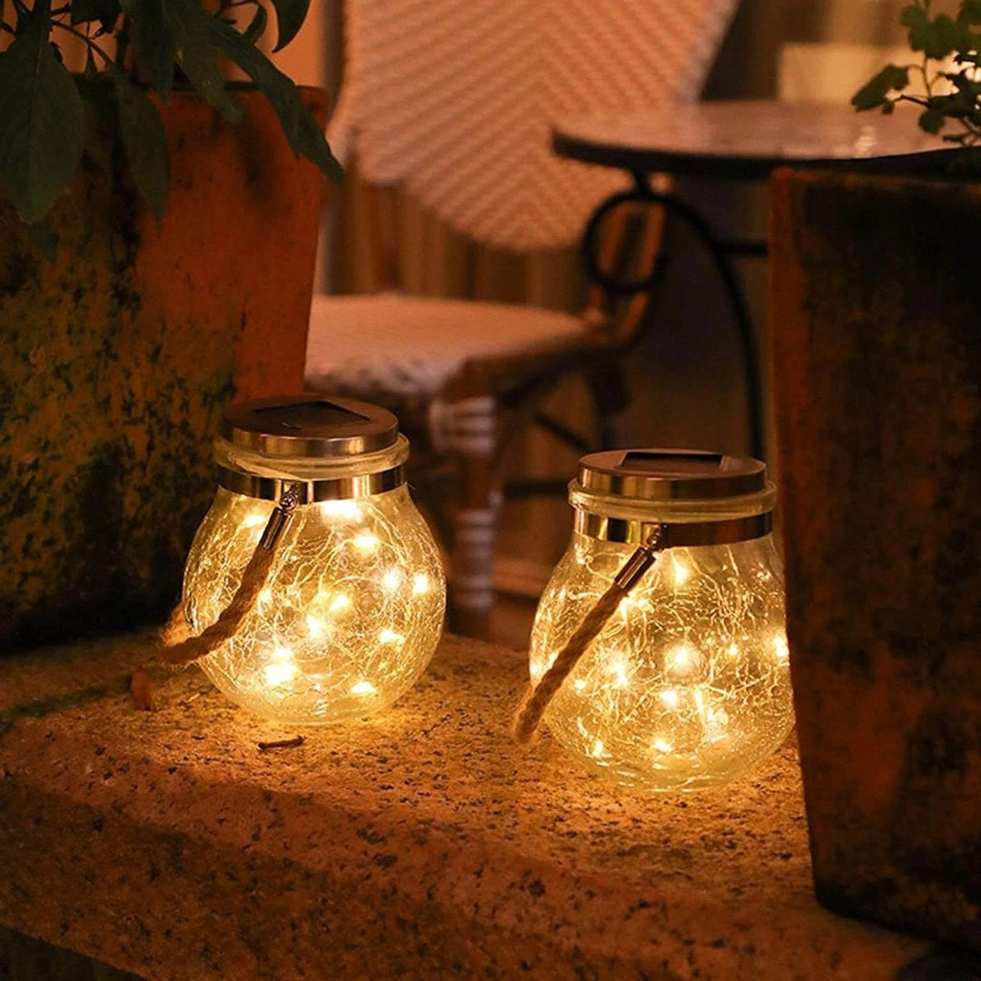 Solar-powered mason jar lights with LED fairy lanterns, designed for outdoor use. The jars are made of glass and feature a waterproof design suitable for various weather conditions. These decorative lights can hang in gardens, patios, or any outdoor space, creating a warm and ambient atmosphere.