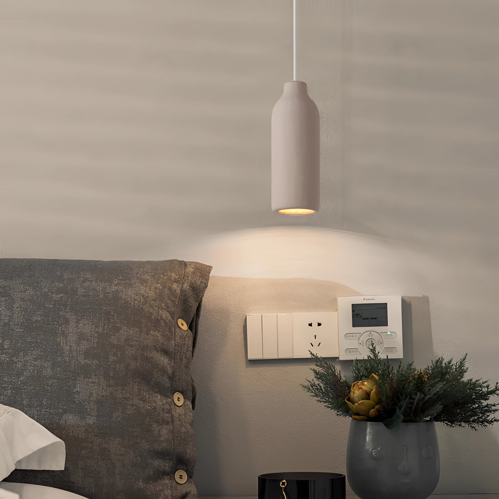 Textured oversized pendant light hanging in a minimalistic dining area with wood accents, surrounded by houseplants and a flowerpot.