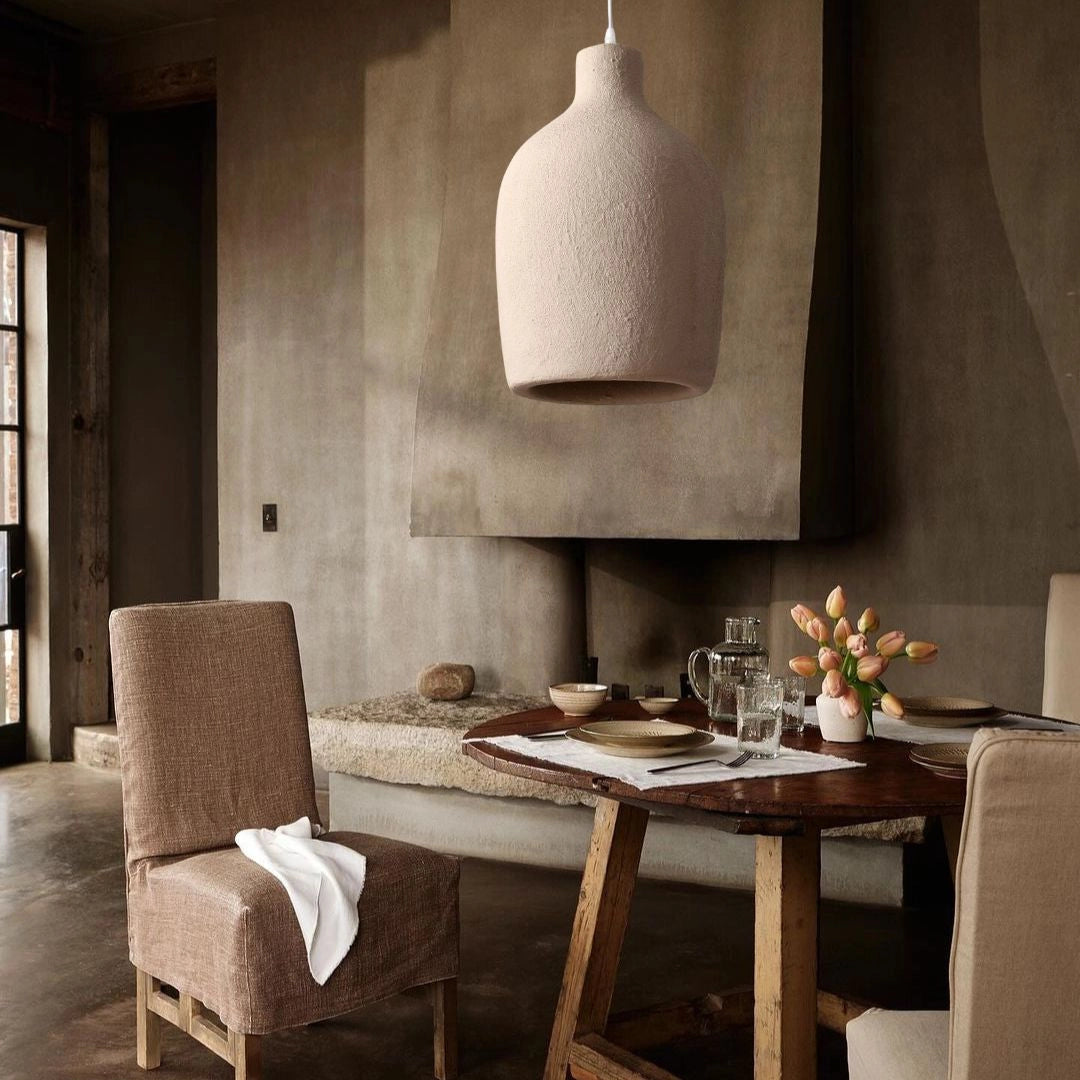 Textured oversized pendant light hanging above a minimalistic dining area with wooden furniture and grey interior design elements.