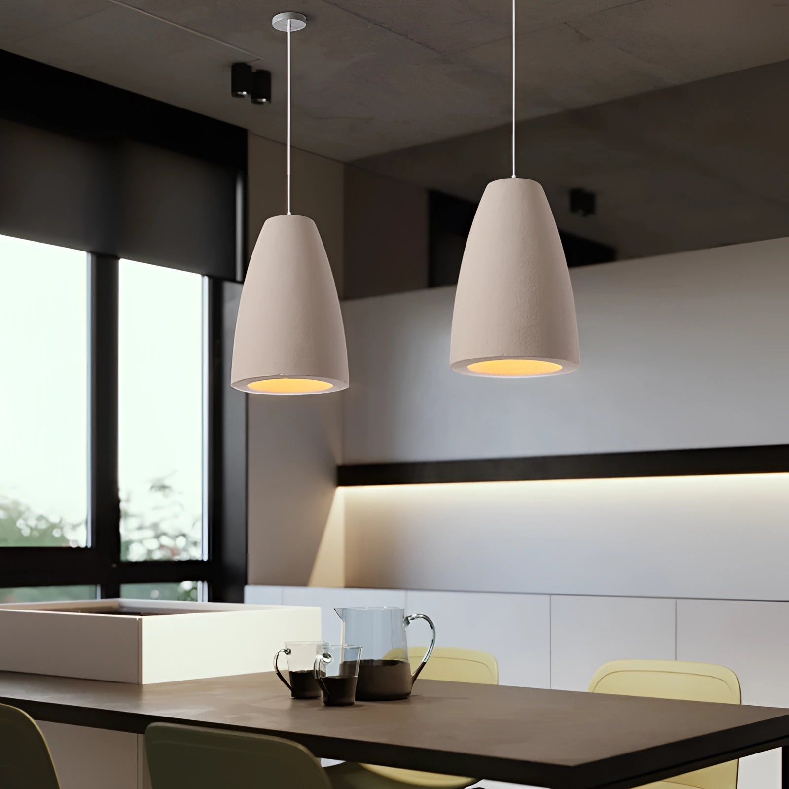 Textured oversized pendant light hanging above a wooden dining table, illuminating a minimalistic dining area with large windows.