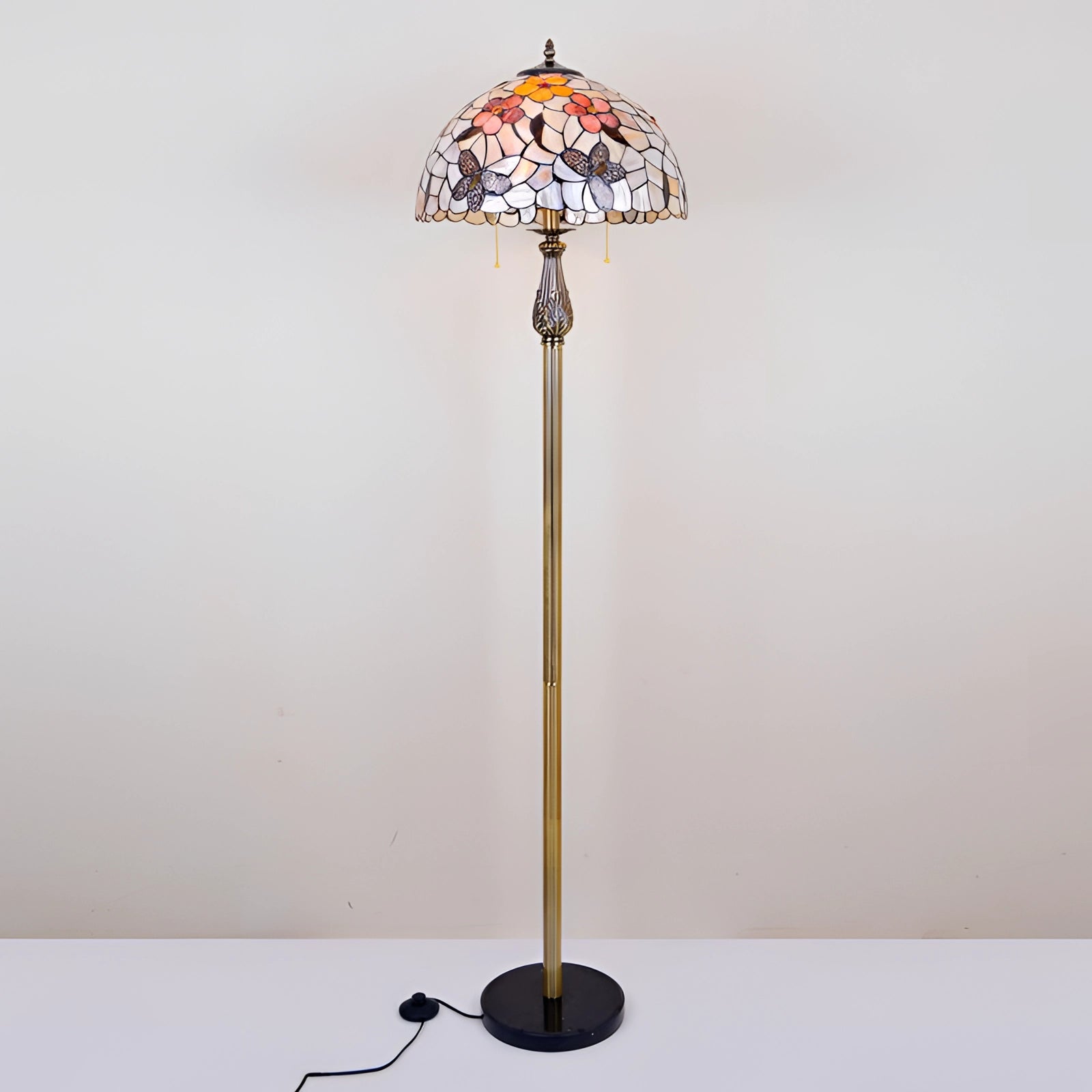 Tiffany-Style Dragonfly Stained Glass Floor Lamp with a detailed brass pole, featuring a colorful glass dragonfly design, set against a background of intricate stained glass patterns.
