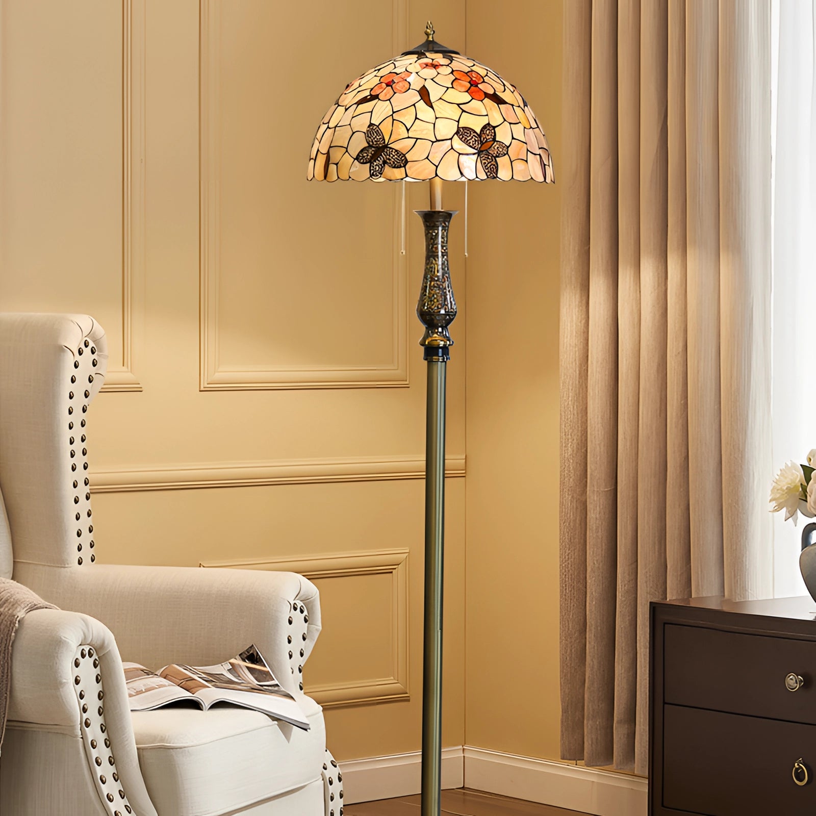 Tiffany-style stained glass floor lamp with dragonfly design, featuring a brass pole, set in a cozy interior with wooden furniture and white curtains.