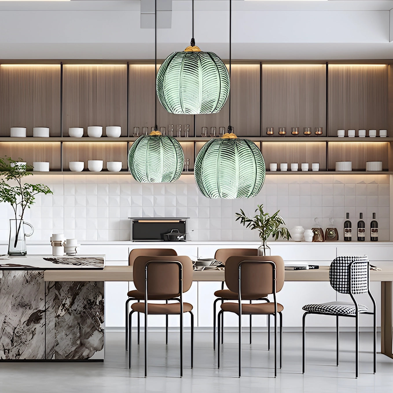 A trio of luxury tropical pendant lights with botanical leaf glass decor, hanging above a table with modern furniture and plants in a stylishly decorated interior.