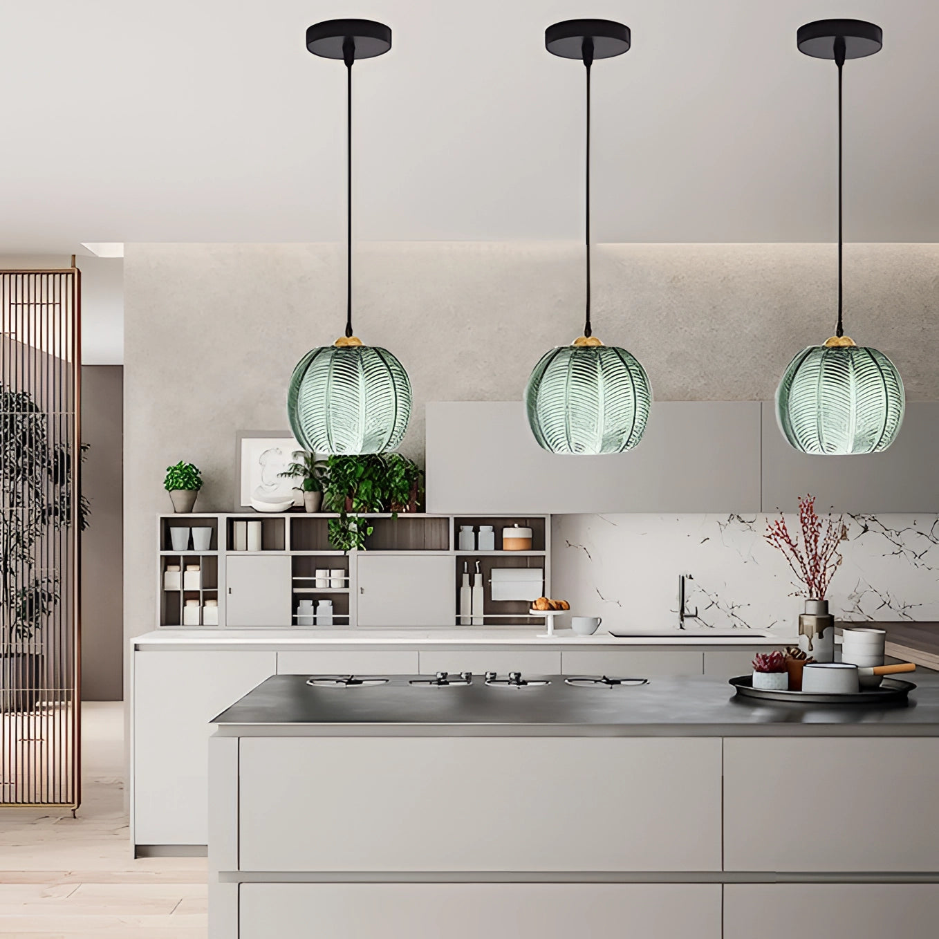 Tropical pendant light trio featuring luxury botanical leaf glass decor hanging in a modern kitchen with white cabinetry and countertops.