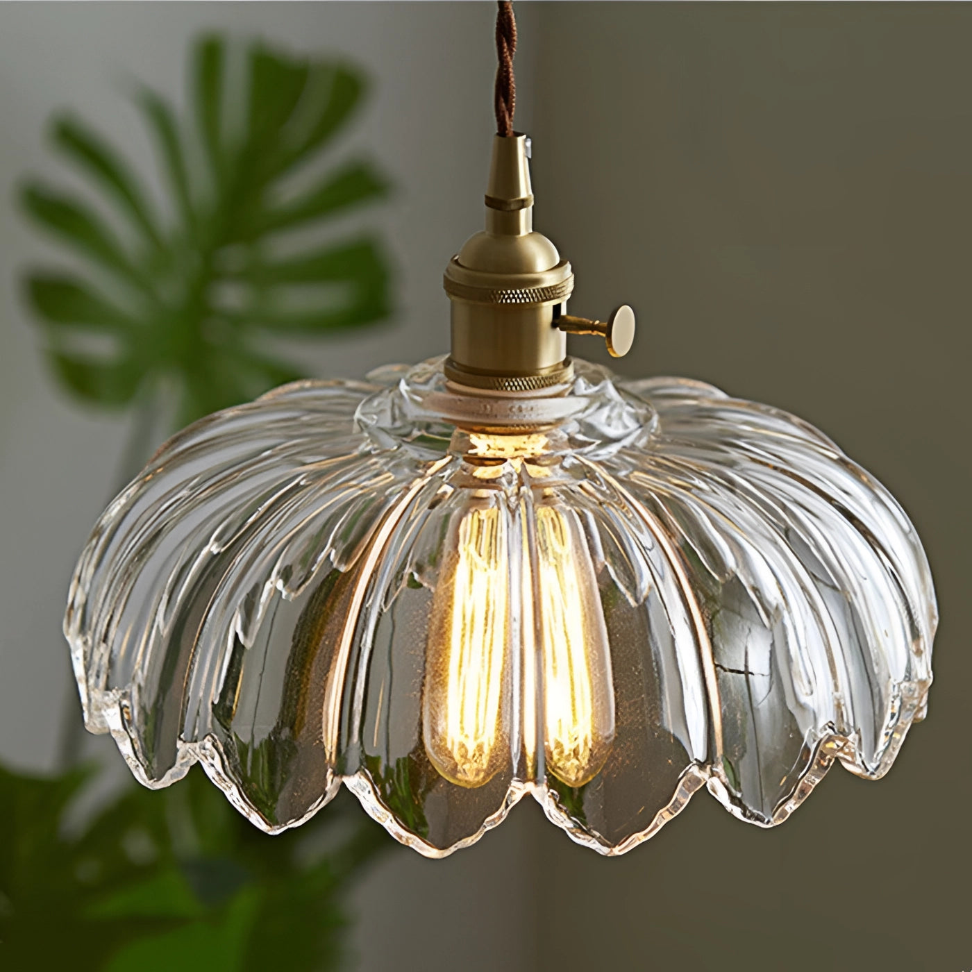 Vintage amber glass pendant light with brass flower petal design, featuring a warm glow and intricate metalwork, resembling a charming ornament.