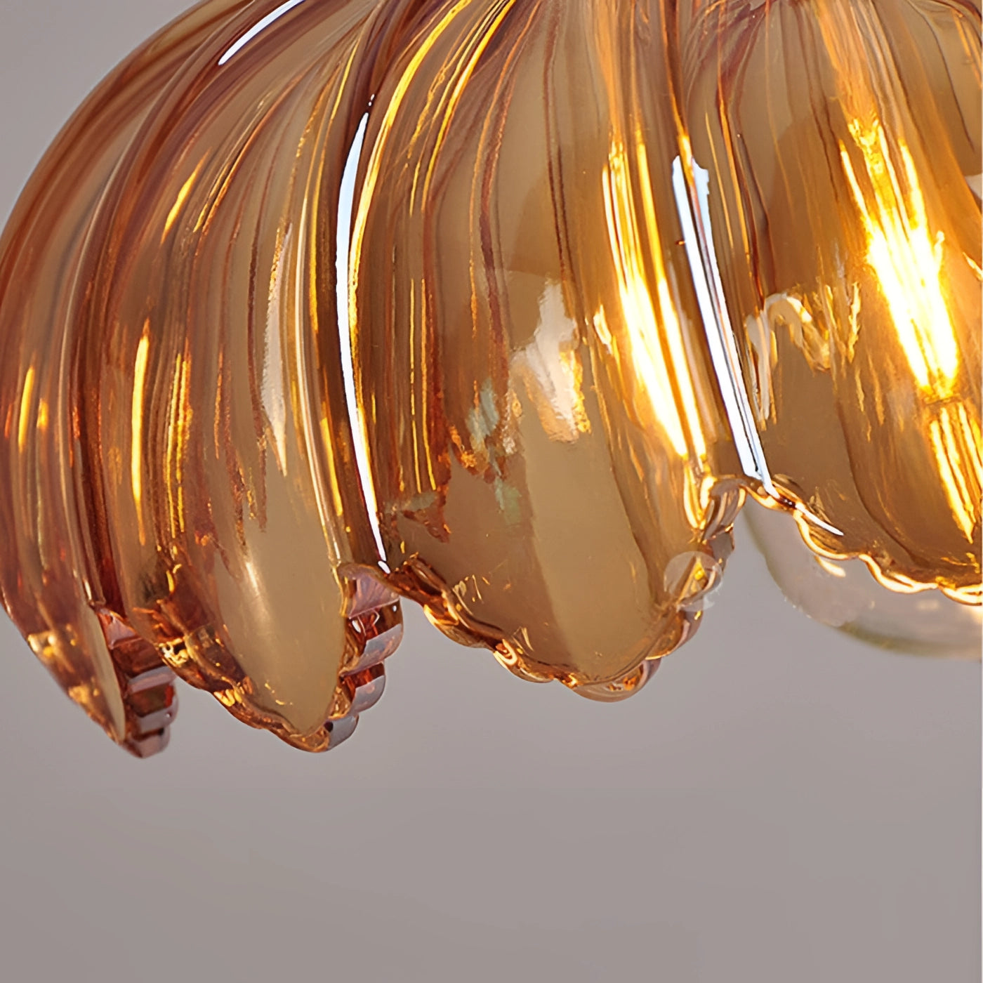 Vintage amber glass pendant light with brass flower petal design, featuring a warm amber hue and elegant circular glass elements hanging from the ceiling.
