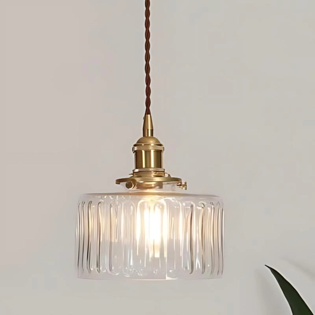 Vintage-style clear glass pendant light with a ribbed design and antique brass hardware, featuring a single fixture hanging from the ceiling.