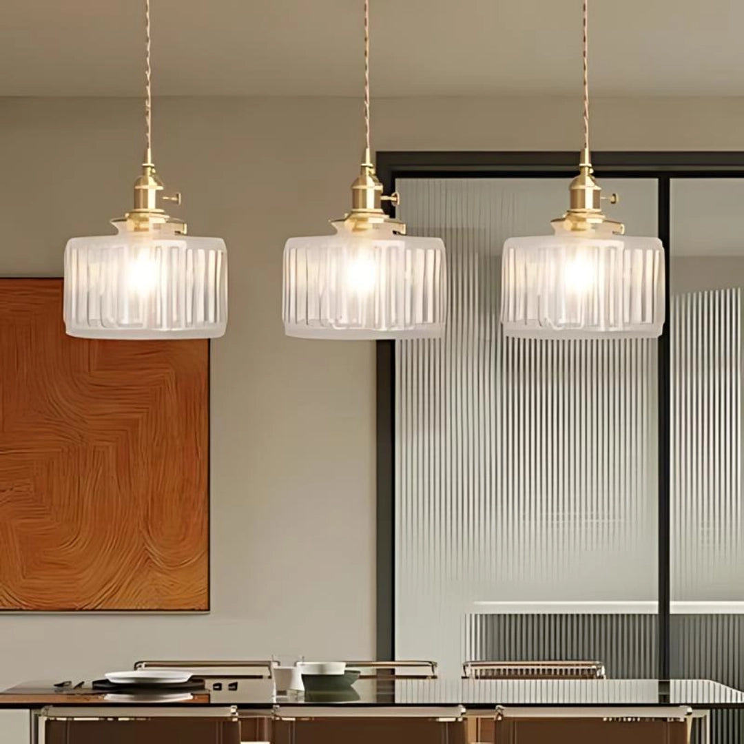 Vintage green glass pendant light with three clear, elongated ribbed glass heads and antique brass fittings, stylishly illuminating an indoor space with a retro-inspired design.