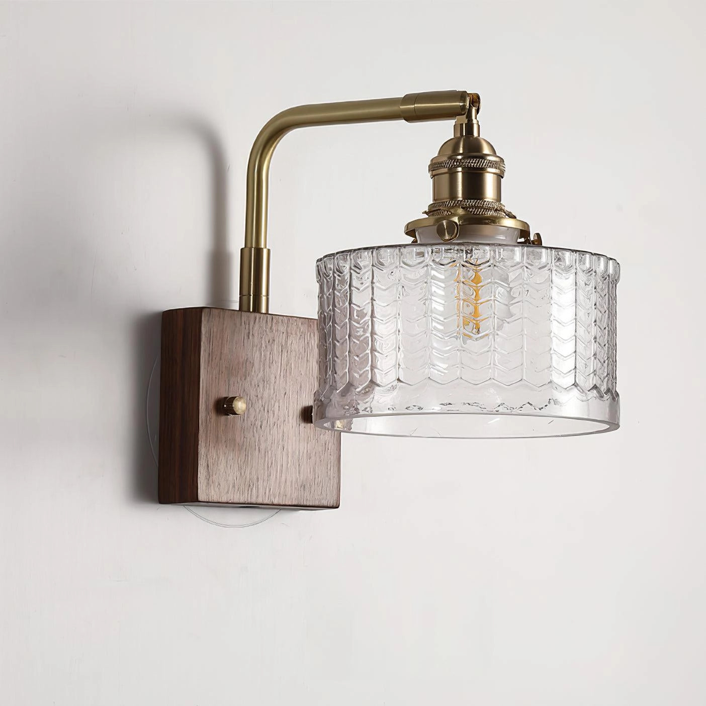 Vintage green glass sconce with a brass arm featuring a fish scale pattern, displayed in a clear glass variant.