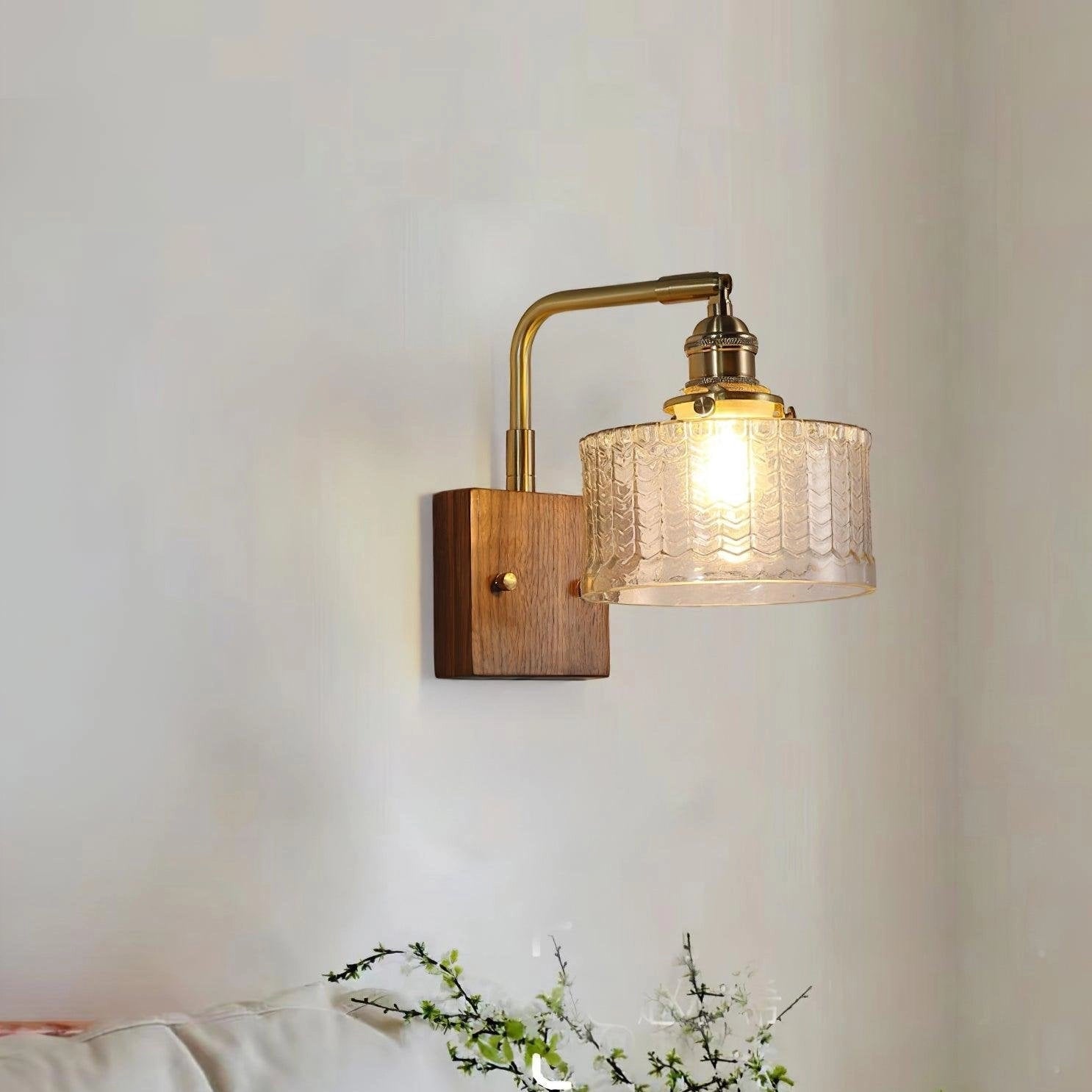 Vintage green glass sconce with a brass arm featuring a fish scale pattern, displayed against a neutral backdrop.