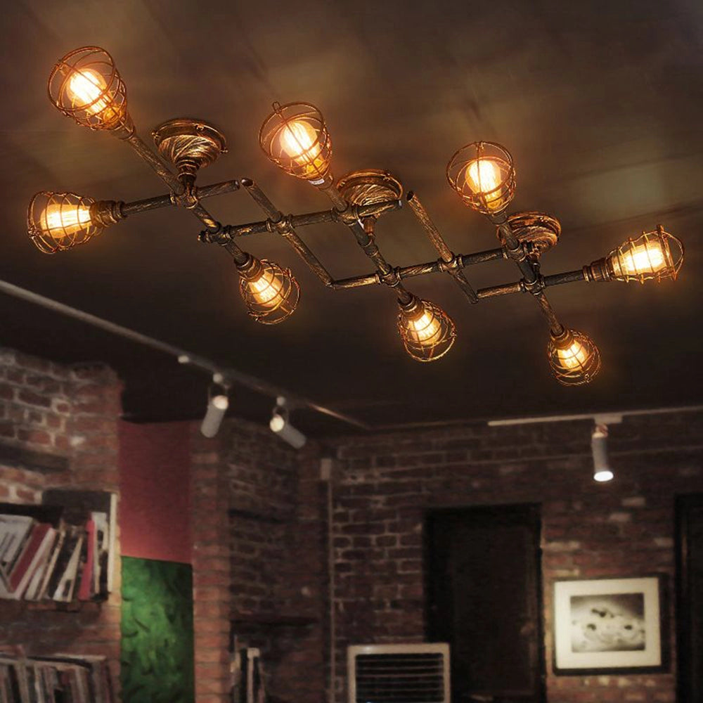 Vintage industrial ceiling light with adjustable track heads in rustic bronze finish, mounted on a ceiling, illuminating a room with wooden accents, picture frames, and a bookcase.