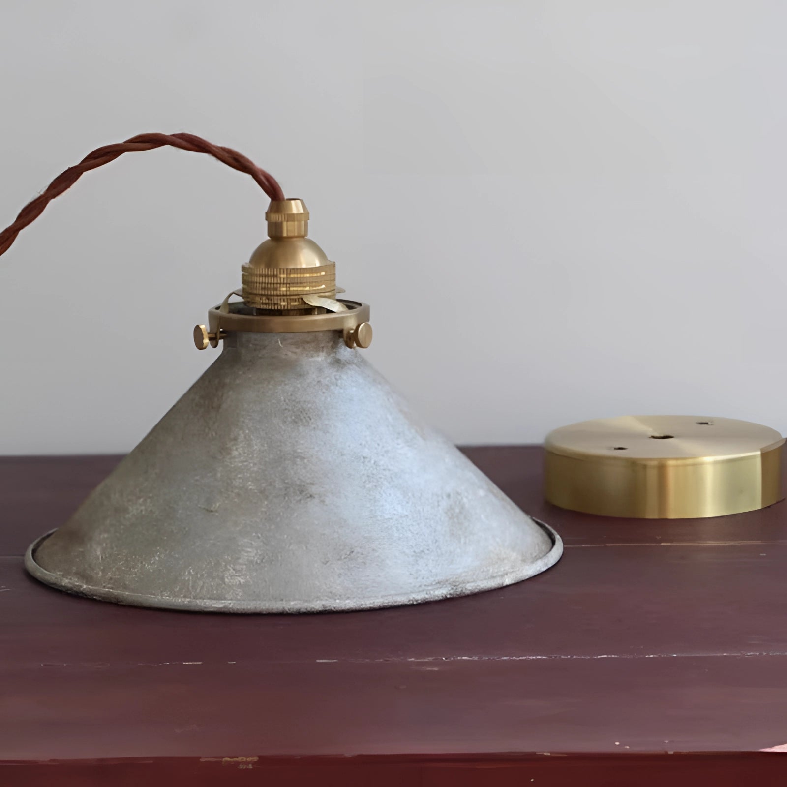 Vintage industrial pendant light featuring an antique brass and distressed blue finish, with a focus on the metal light fixture in a still life setting.