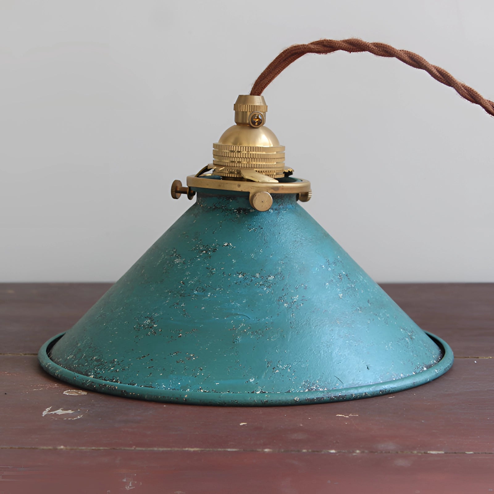 Vintage industrial pendant light featuring an antique brass finish and distressed blue accents with a cone-shaped design.
