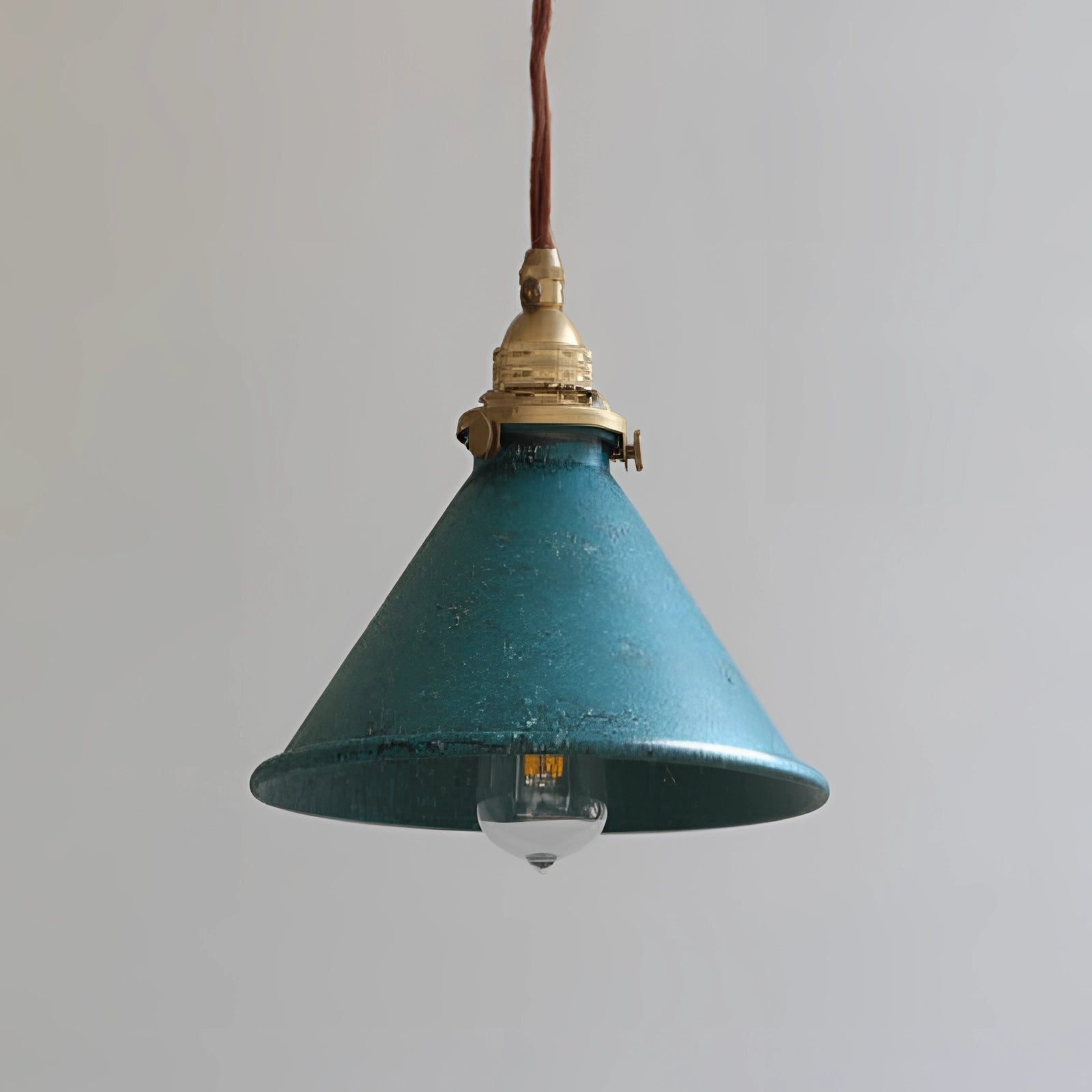 Vintage industrial pendant light with an antique brass finish and distressed blue shade, featuring a conical shape and ceiling fixture design.