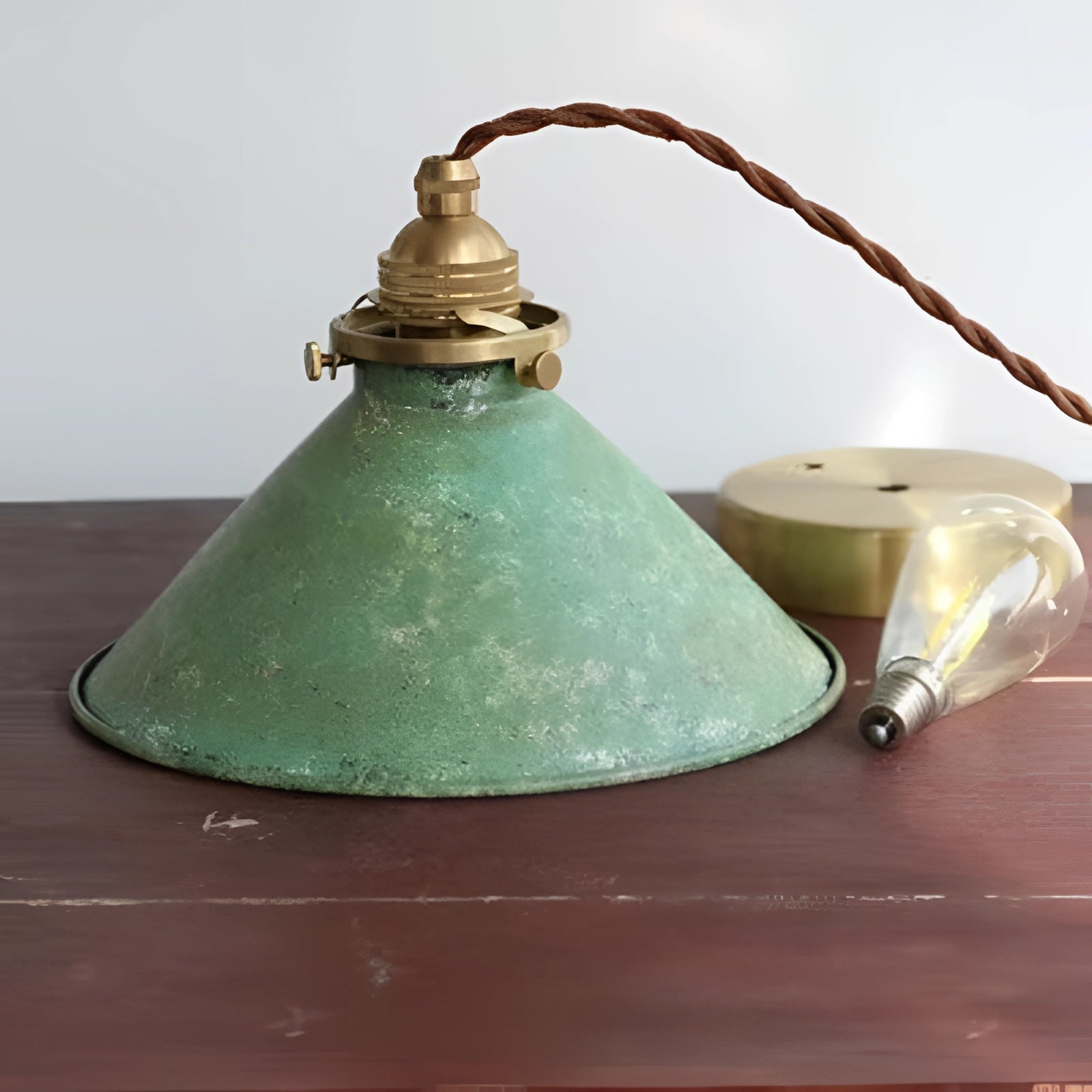 Vintage industrial pendant light with an antique brass finish and distressed blue accents, featuring a metal and glass construction, designed to hang from the ceiling.