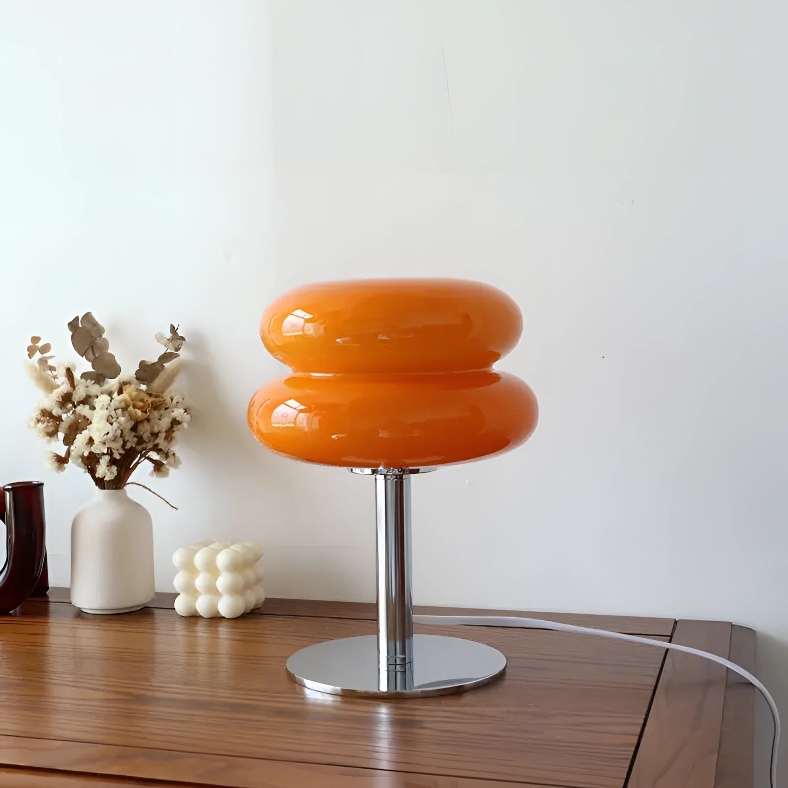 Orange mushroom lamp with a chrome base, featuring a retro 1970s design; displayed on a wooden surface with a modern and artistic appeal.