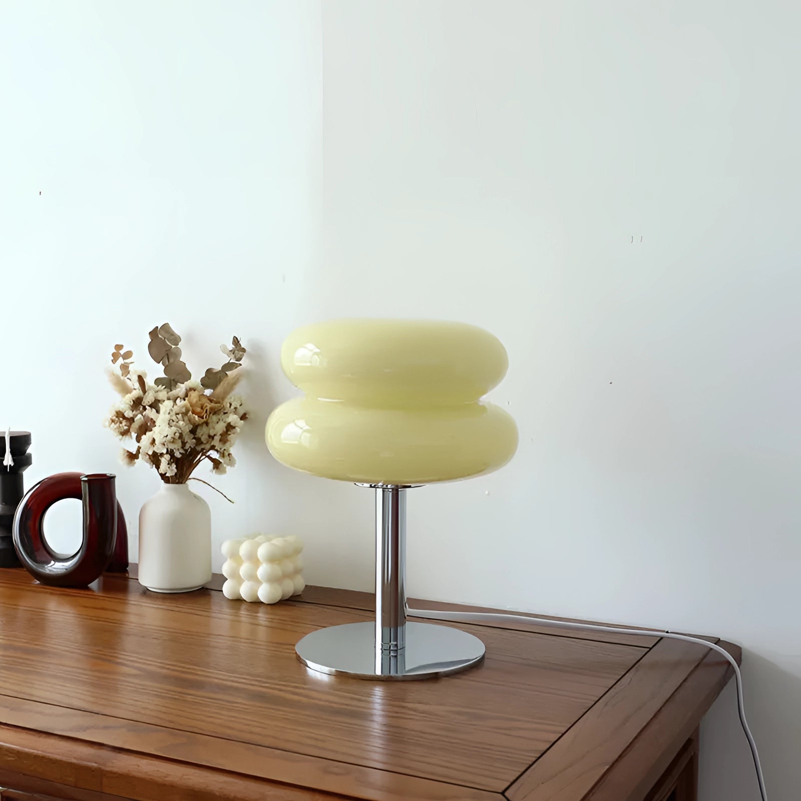 A vintage 1970s orange mushroom lamp with a chrome modern retro design, placed on a wooden table beside decorative vases and potted plants.
