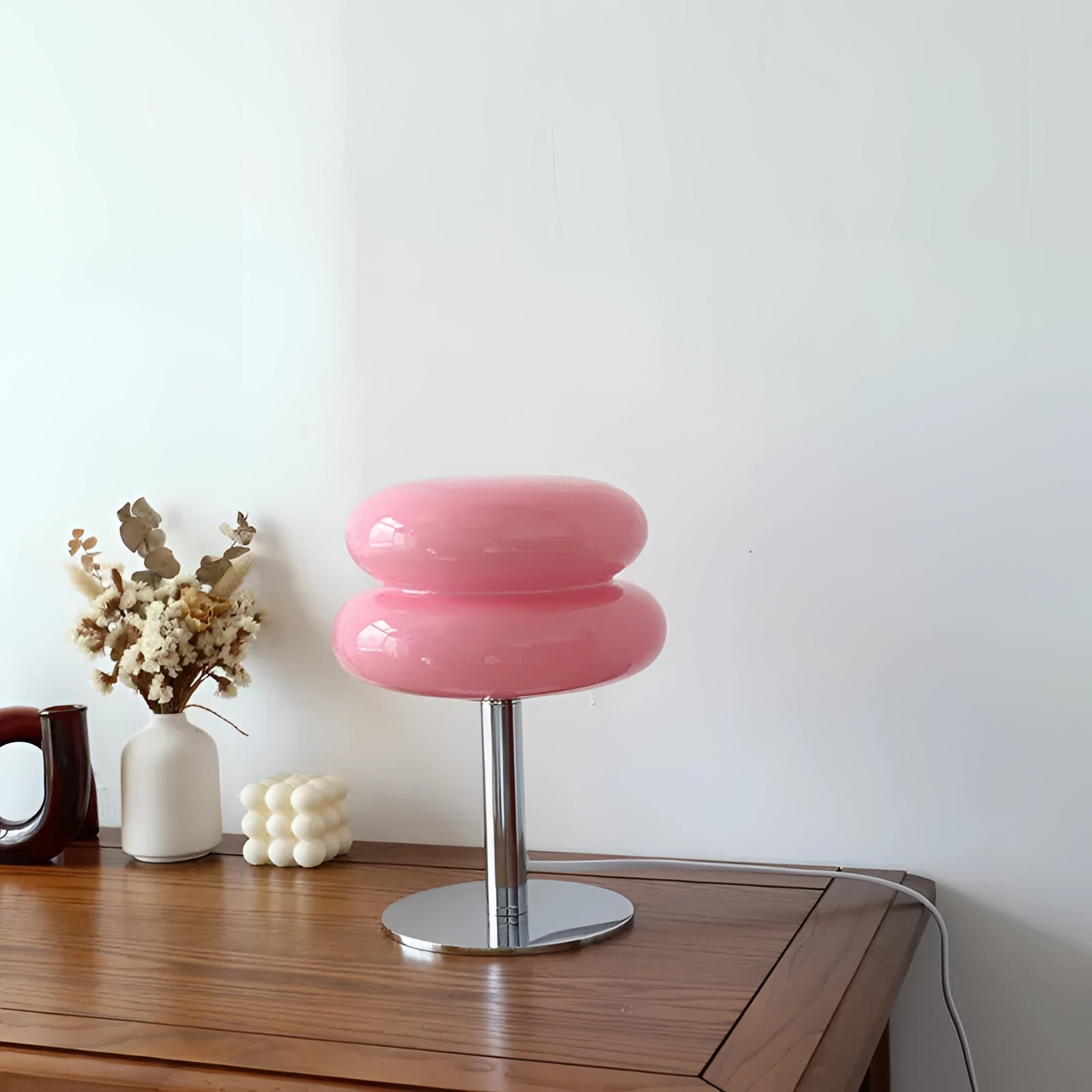 1970s orange mushroom lamp with a chrome base in a modern retro design, placed on a wooden table in a stylish interior setting, with a rose-toned hue.