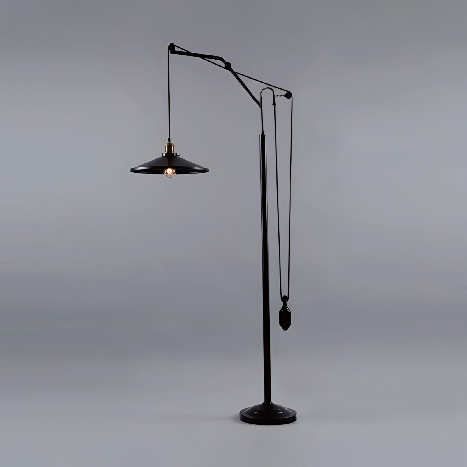 Adjustable industrial pulley floor lamp with a vintage black finish, featuring a transparent glass shade and an Edison bulb, showcasing metal and aluminum elements for a stylish and balanced lighting fixture.
