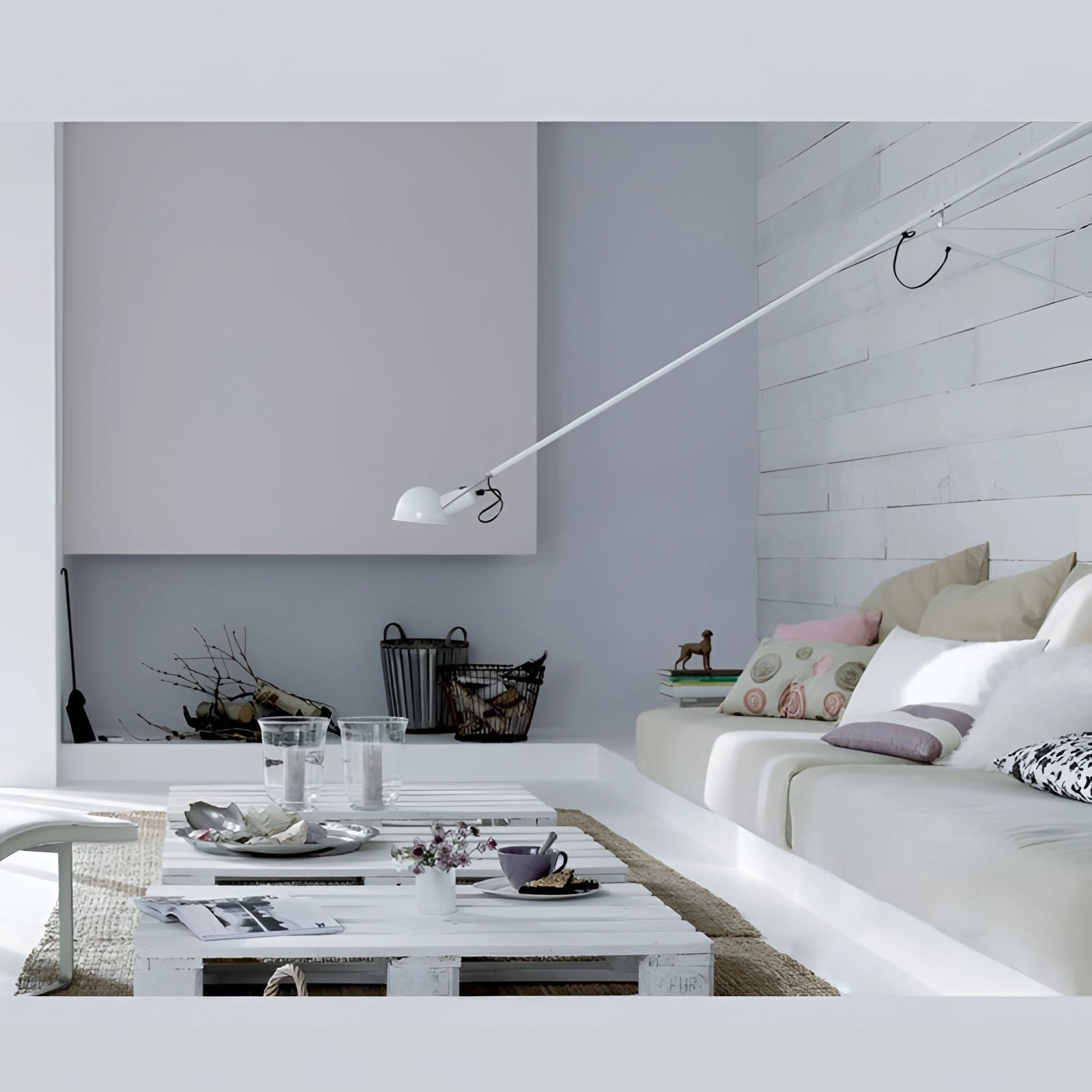 Adjustable industrial swing arm wall lamp in sleek black with a modern design, installed in a stylish living room setting featuring a grey couch, wooden table, and contemporary interior design elements.