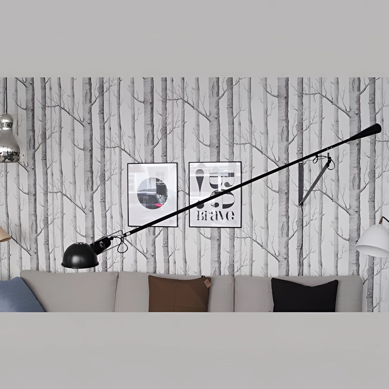 Black adjustable industrial swing arm wall lamp with a sleek, modern design mounted on a wall in a monochrome room setting, featuring metal construction and situated near a window.