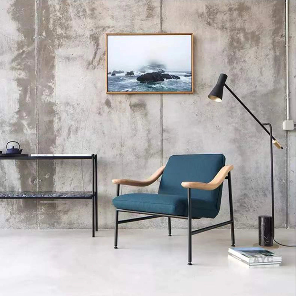 Adjustable Nordic floor lamp in black and gold with a three-color change feature, positioned in a stylish interior setting next to a wooden chair on a grey floor.