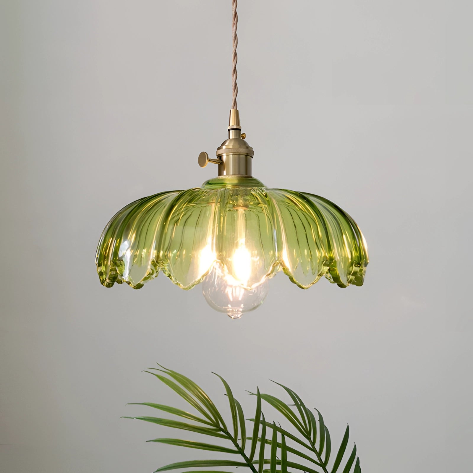 Amber Glass Pendant Light with Vintage Flower Design and Antique Brass Finish, hanging from the ceiling, illuminated light bulb, against a neutral background with ornamental details.
