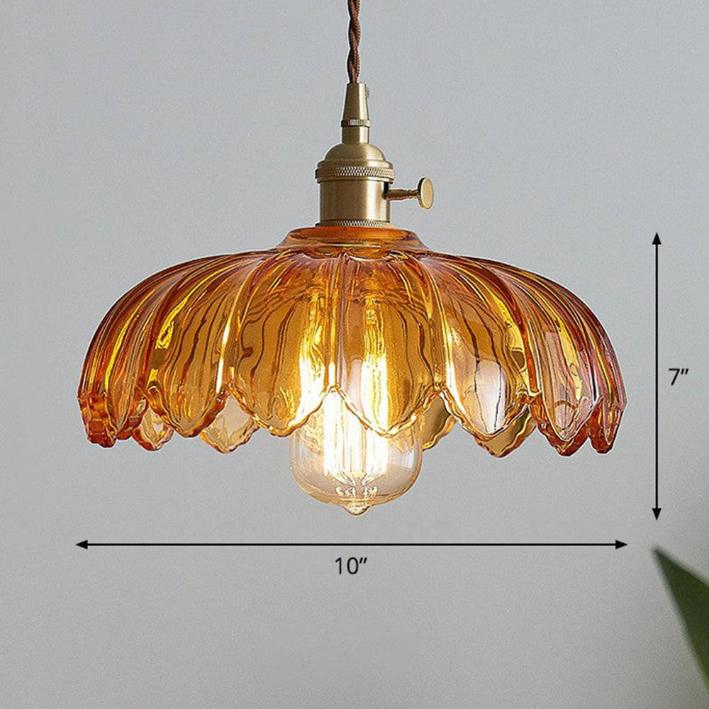 Vintage amber glass pendant light with antique brass finish, featuring a flower design and hanging from a ceiling.