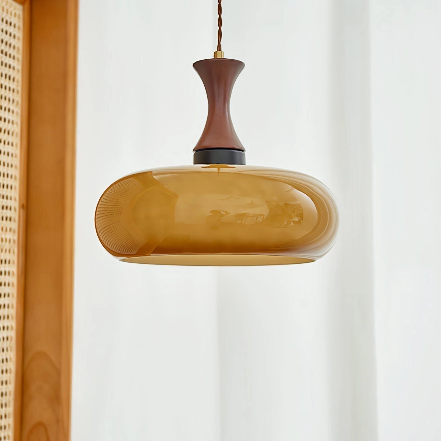 Amber glass retro pendant light with a mid-century modern design, featuring a brown glass shade in an oval shape and a D11 size, suspended by metal fittings.