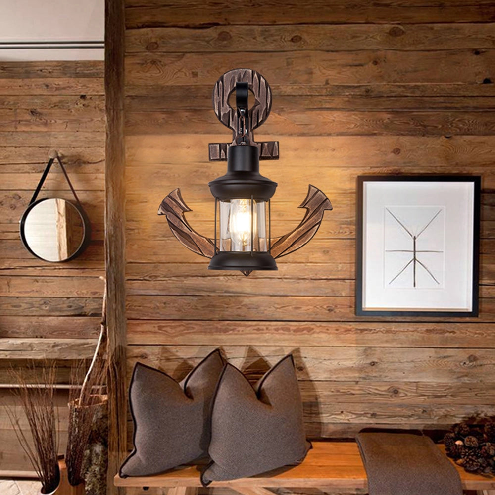 Anchor-shaped nautical wall sconce with a rustic coastal design, featuring a wooden texture and a brown finish, providing ambient lighting in an interior setting.