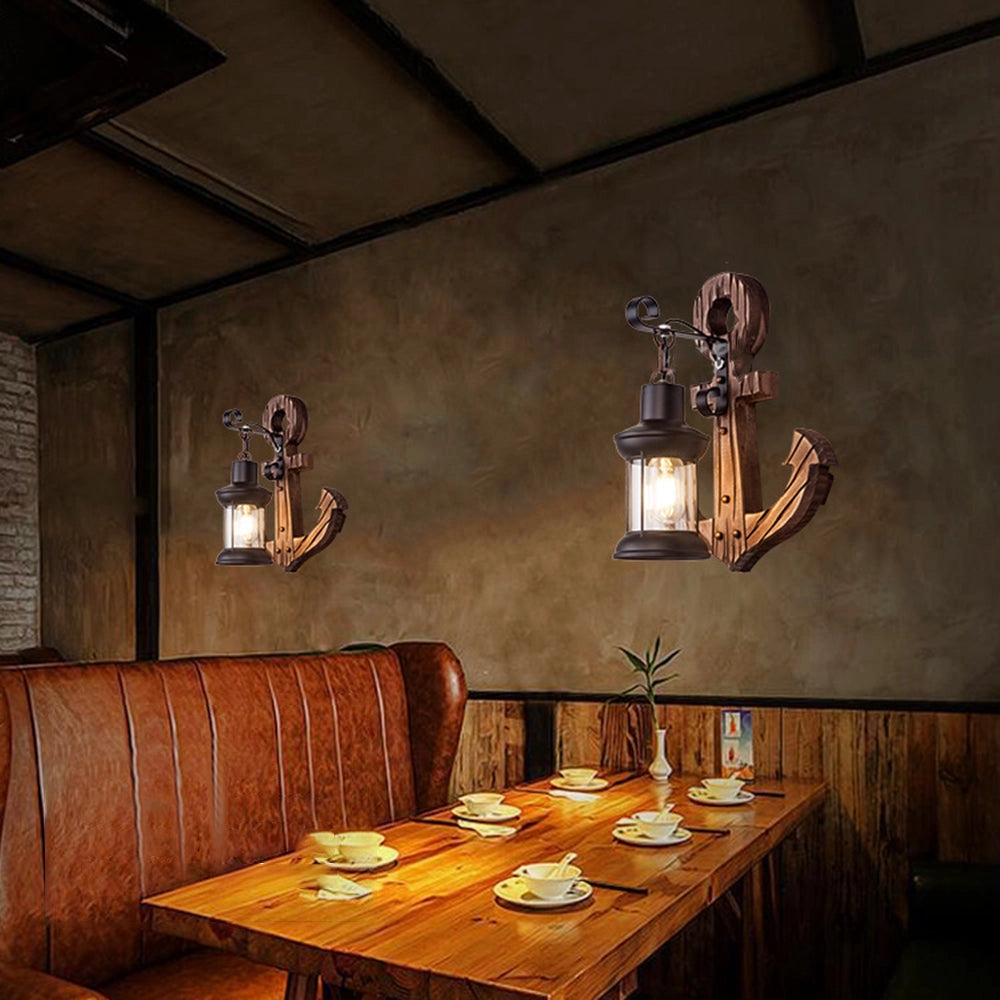 Anchor-shaped nautical wall sconce with a rustic coastal design, mounted on a wooden wall in an interior space.
