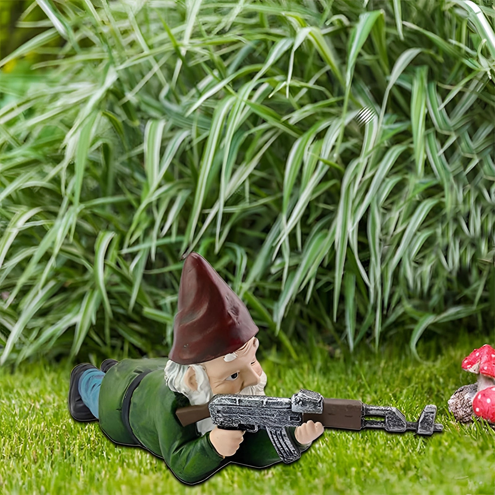 Armed warrior garden gnome statue wearing sunglasses and a camouflage hat, holding an AK-47, standing amidst grass.