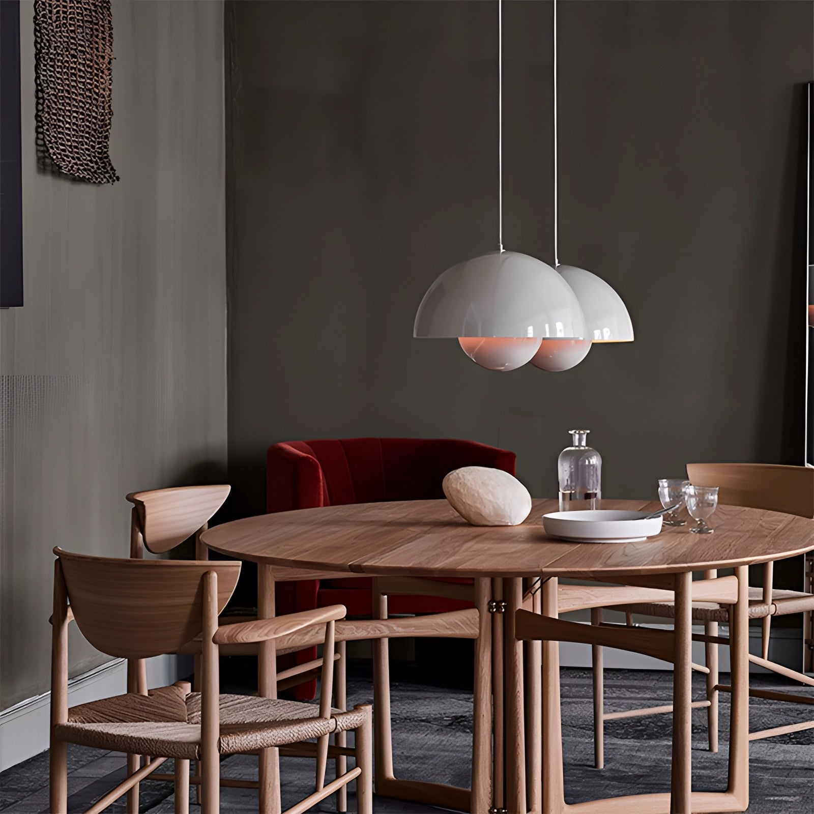 Modern retro yellow, white, and orange pendant lights hanging over a stylish wooden table set with tableware, surrounded by comfortable chairs in a well-designed interior space.