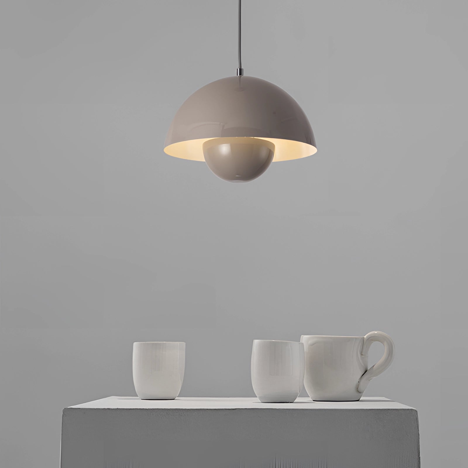 Modern retro pendant lights in yellow, white, and orange with grey and wooden accents, hanging above a table set with drinkware and dishware.
