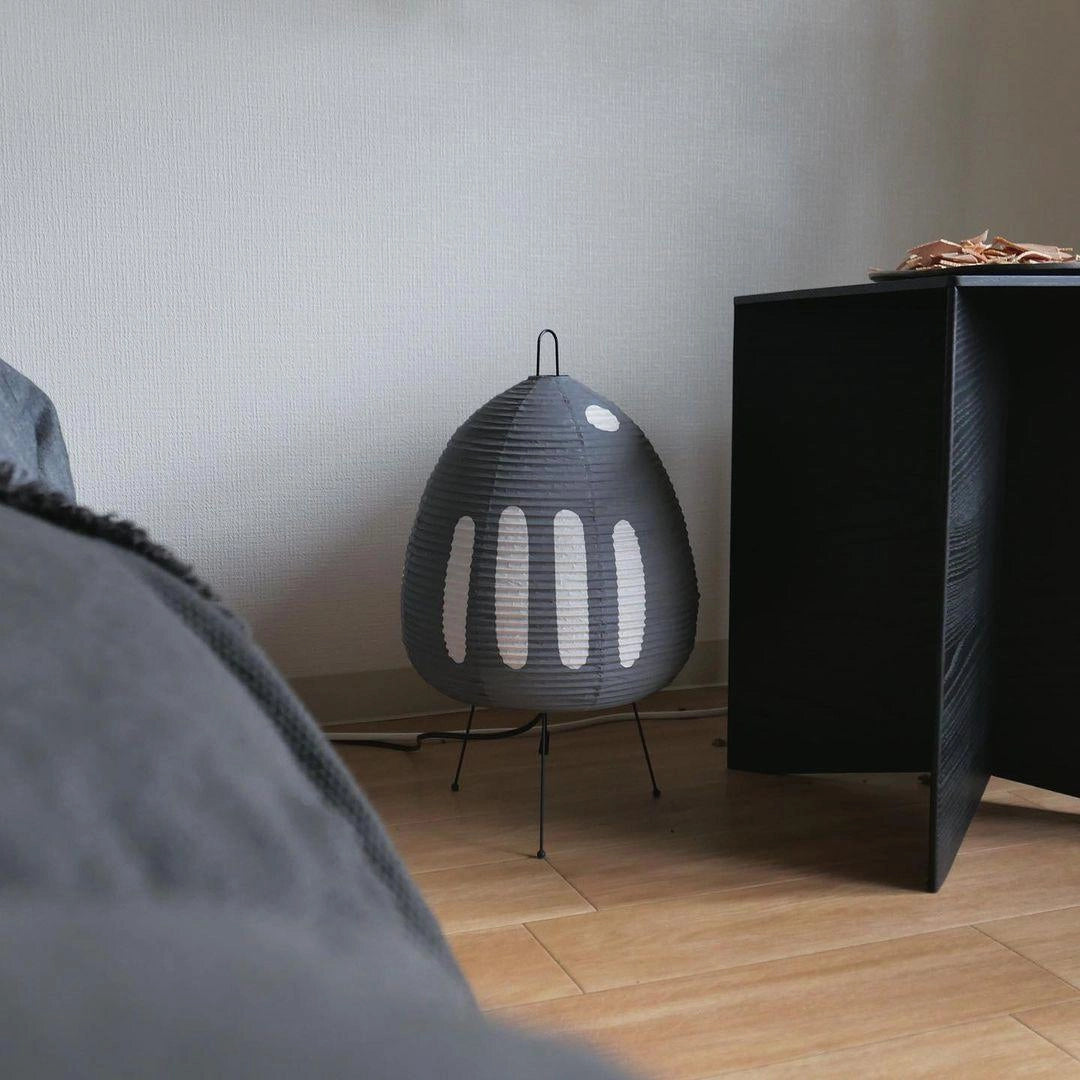 Beehive Sculptural Tripod Floor Lamp with unique design featuring a grey lampshade and wooden tripod base, placed on a hardwood floor in a modern interior setting.