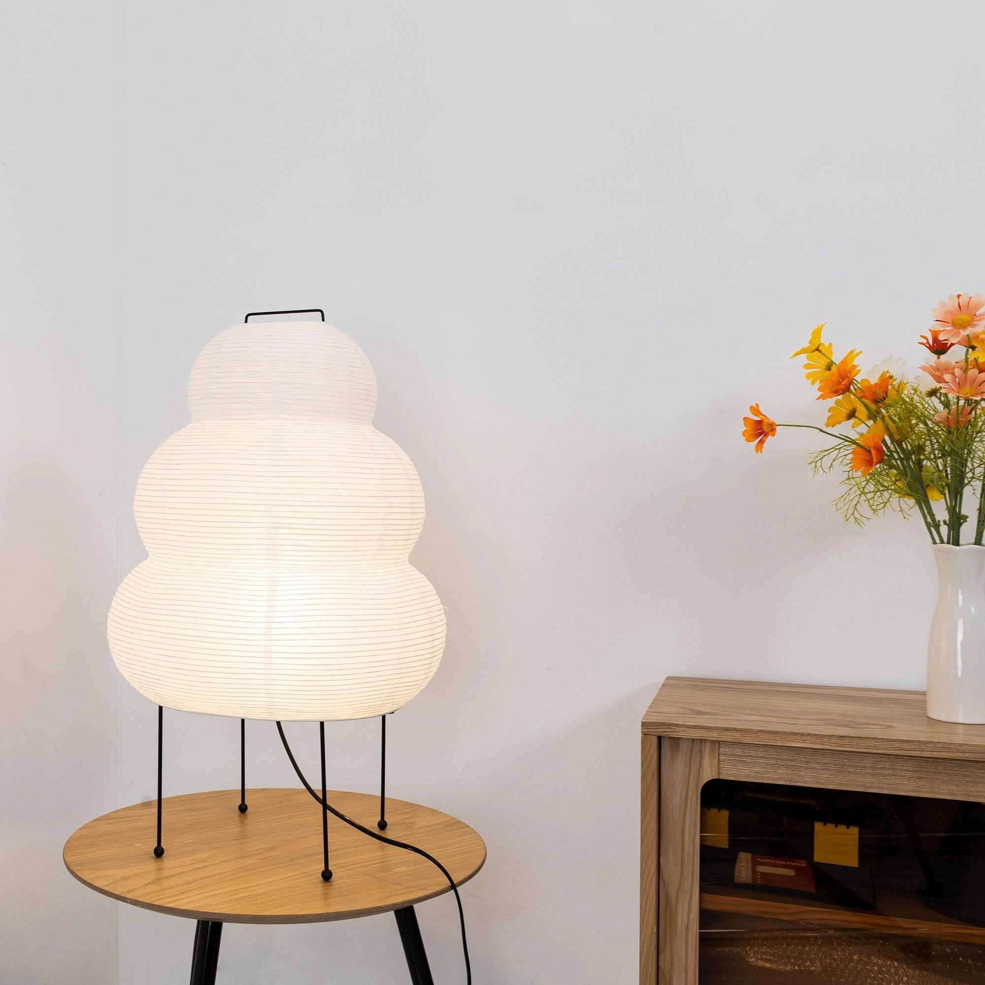 Beehive Sculptural Tripod Floor Lamp in a stylish interior setting with wood furniture and a potted plant.