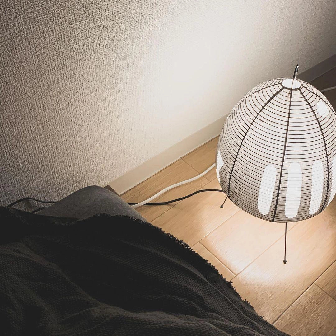 Beehive Sculptural Tripod Floor Lamp with wooden legs and unique beehive-shaped shade, placed on a wooden floor.